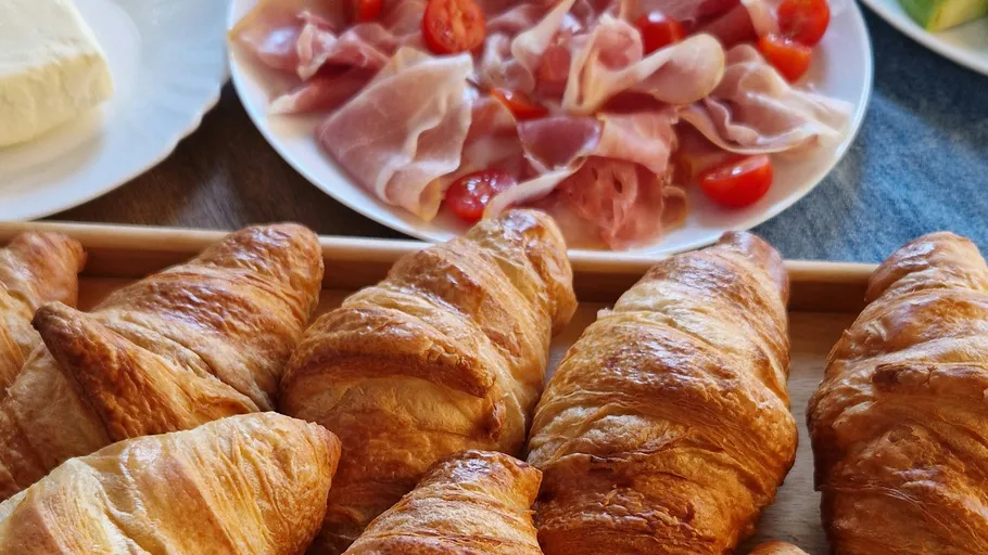 Croissants auf Tablett, Schinken und Tomaten daneben.