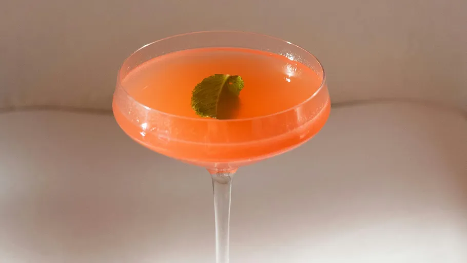 Pinkfarbener Cocktail mit Minzblatt oben.