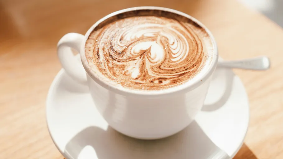 Tasse Cappuccino mit Latte Art, Holztisch.