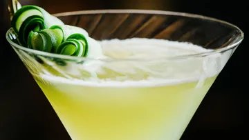 Grüner Cocktail im Glas mit Gurkengarnitur.