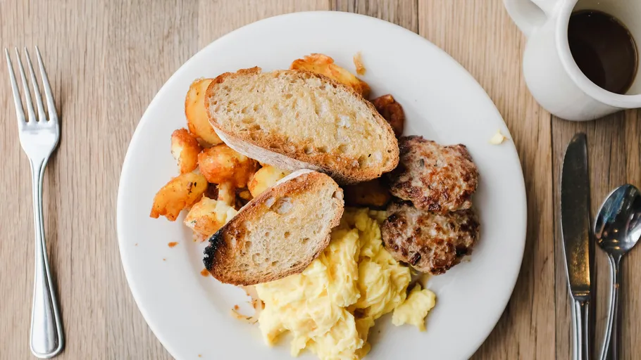 Frühstücksteller mit Eiern, Kartoffeln, Toast, Wurst.