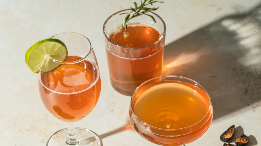 Drei Cocktails mit Garnierungen auf Tisch.