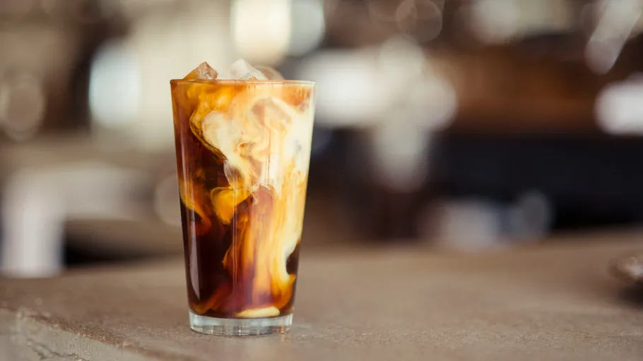 Eiskaffee mit Milchwirbel auf Theke.