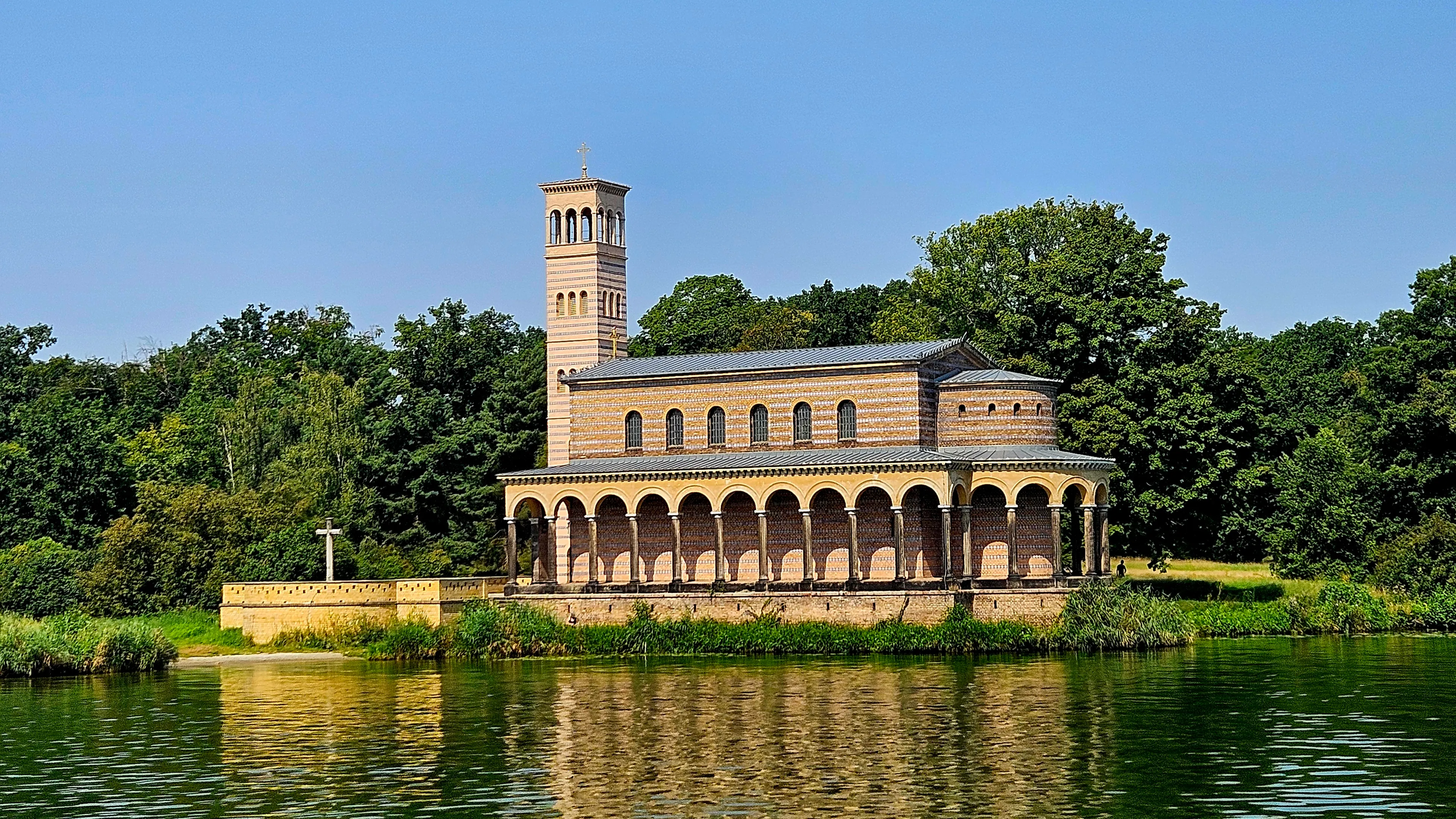 Brick church beside a lake surrounded by trees.