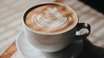 Cup with latte art on table.