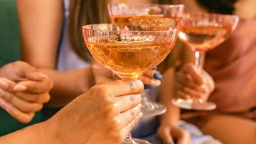 Hände stoßen mit Sektgläsern auf Party an.