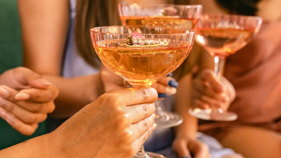 Hands clinking champagne glasses at party.