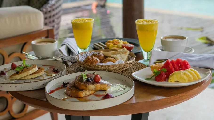 Frühstück mit Pfannkuchen, Obst und Getränken am Pool.
