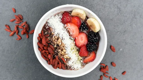 Bowl of fruit and nuts on gray surface.