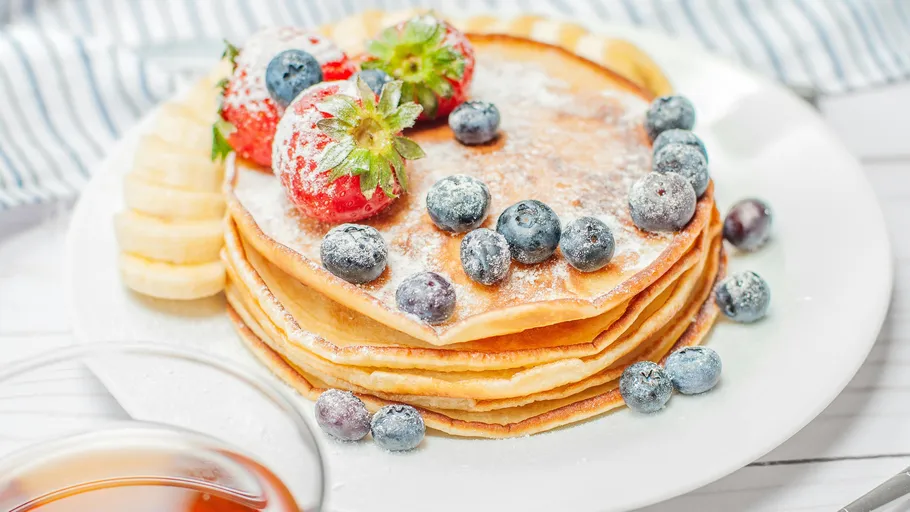 Stack of pancakes with berries, powdered sugar.