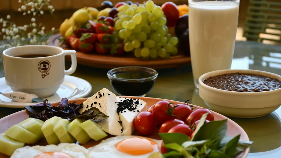 Frühstück mit Eiern, Obst, Kaffee und Milch.