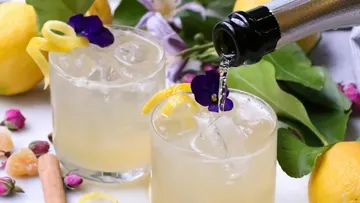 Zwei Cocktails mit Blumen und Zitronengarnitur.