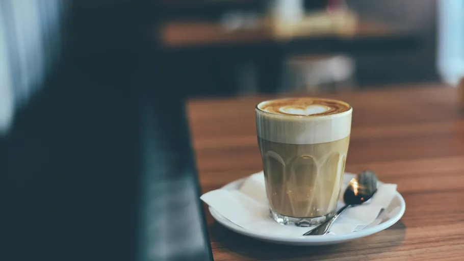 Latte with heart design on wooden table.