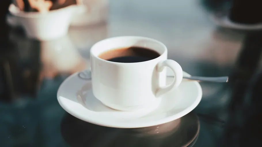 Kaffeetasse auf einem reflektierenden Glastisch.