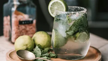 Glass of mojito with lime and mint on table.