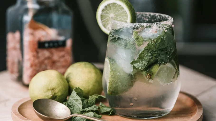 Glas Mojito mit Limette und Minze auf Tisch.
