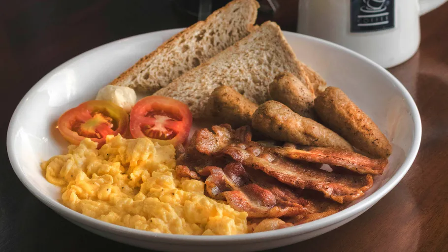 Frühstücksteller mit Eiern, Speck, Würstchen, Toast.