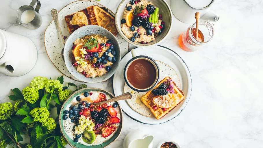 Verschiedene Frühstücksgerichte mit Früchten auf Tisch.