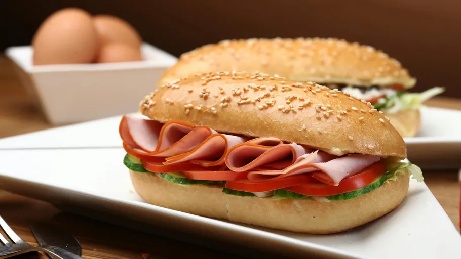 Sliced ham sandwich on white plate.