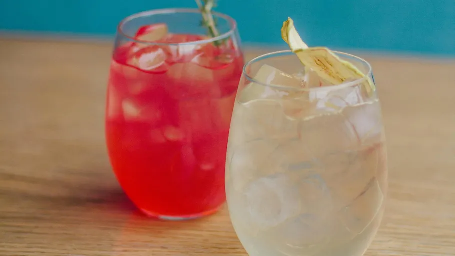 Zwei Cocktails mit Eis auf einem Holztisch.