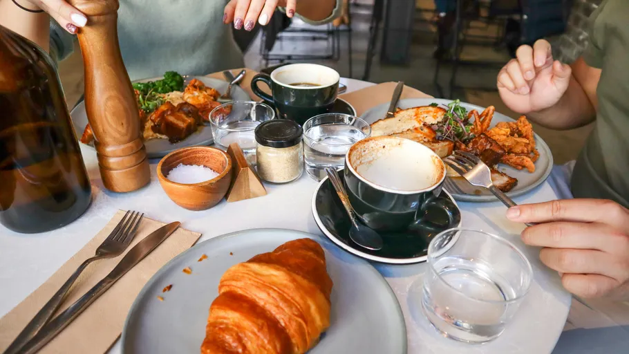 Leute frühstücken an einem Cafétisch.