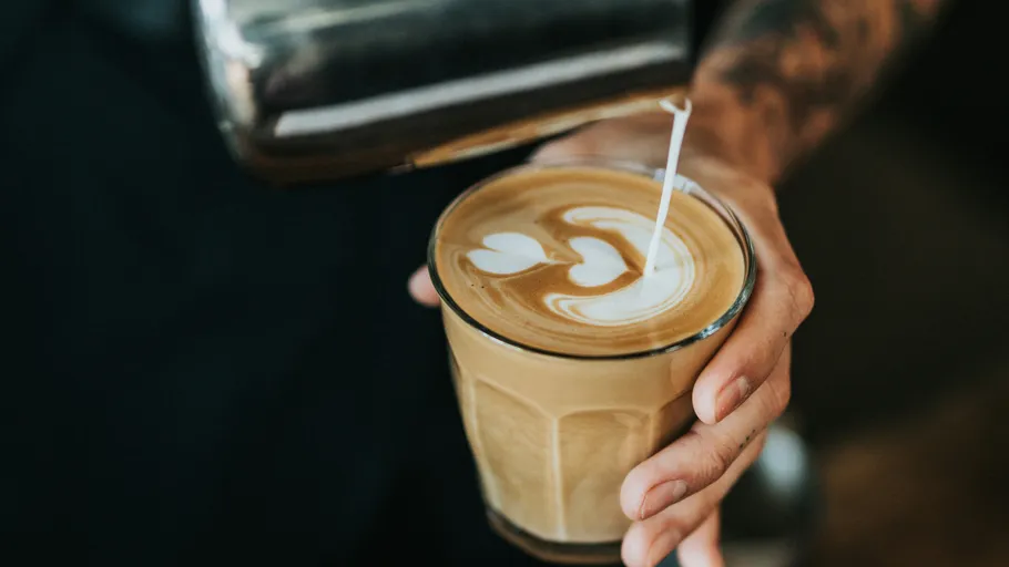 Barista gießt Latte Art in ein Glas.