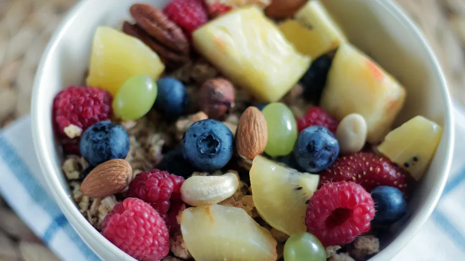 Bowl of cereal topped with fruits and nuts.