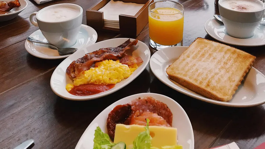 Breakfast plates with bacon, eggs, toast.