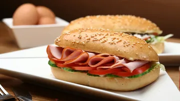Sandwich with ham and vegetables on plate.