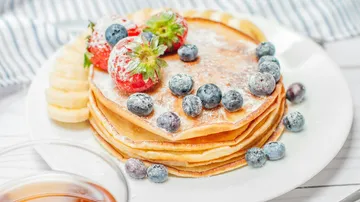 Pancakes topped with berries on plate.