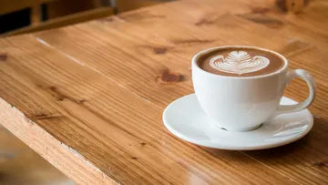 Coffee cup with art on wooden table.