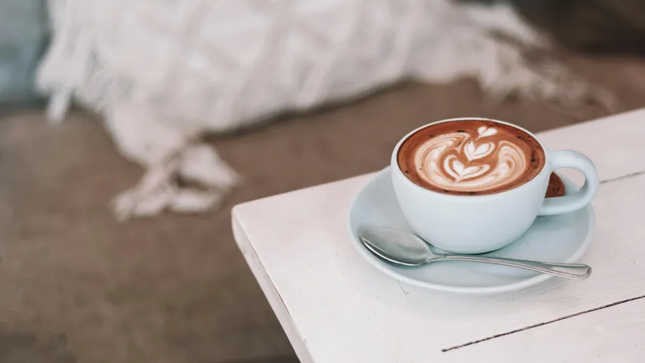 Latte-Kunst in weißer Tasse auf Tisch.