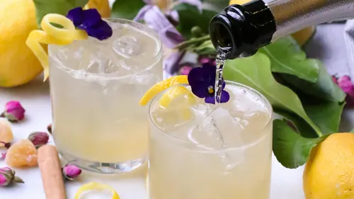Two cocktails with lemon and purple flowers.