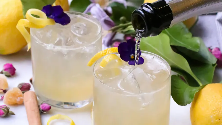 Zwei Cocktails mit Zitrone und violetten Blumen.