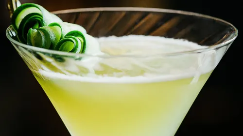 Green cocktail with cucumber garnish.