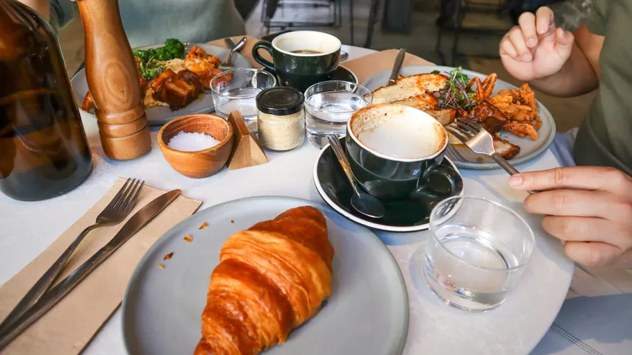 Frühstückstisch mit Croissant und Kaffee.
