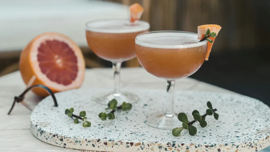 Zwei Cocktails mit Grapefruit-Garnitur auf Tablett.