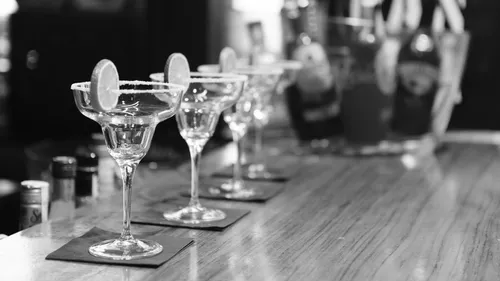 Empty margarita glasses with lime on bar.