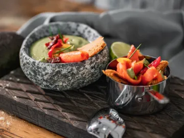 Bowl of guacamole and nachos on wooden board.
