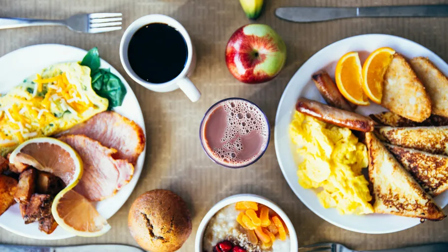 Two breakfast plates with beverages and fruit.