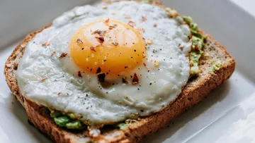 Spiegelei auf Avocado-Toast, weißer Teller.