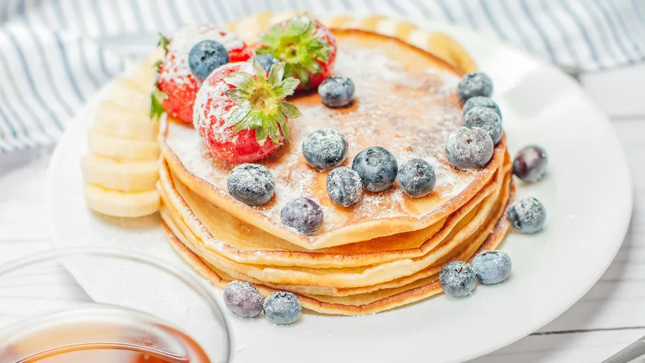 Pfannkuchen mit Beeren und Banane auf einem Teller.