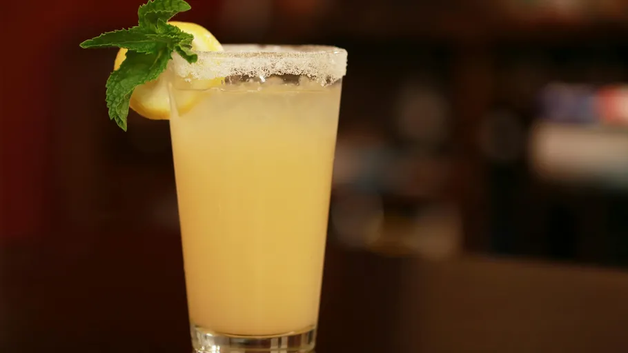 Zitronencocktail mit Minzegarnitur auf Bartresen.