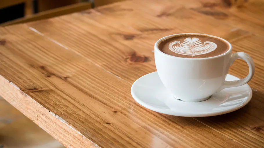 Tasse Cappuccino mit Latte Art auf Tisch.