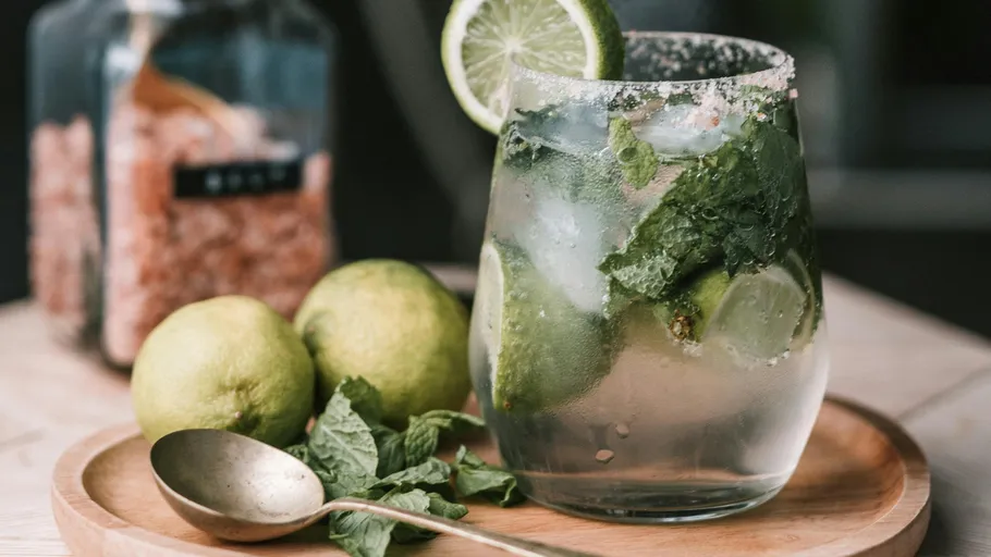 Mojito-Cocktail mit Limette und Minze auf Tisch.