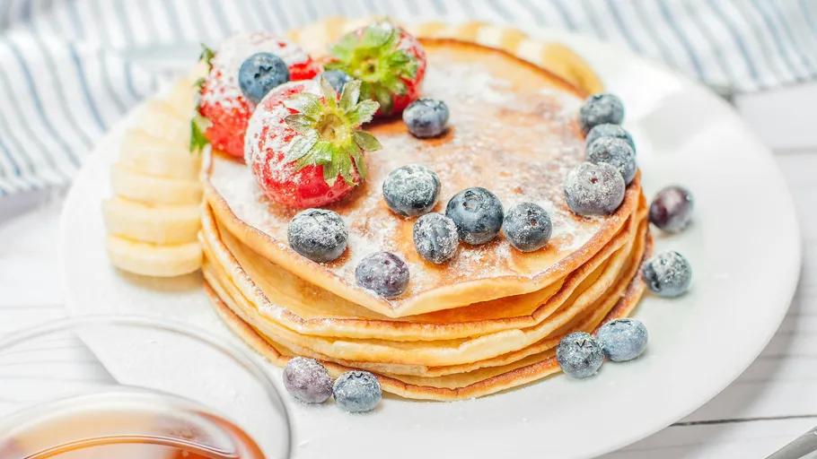 Pancakes topped with strawberries and blueberries.