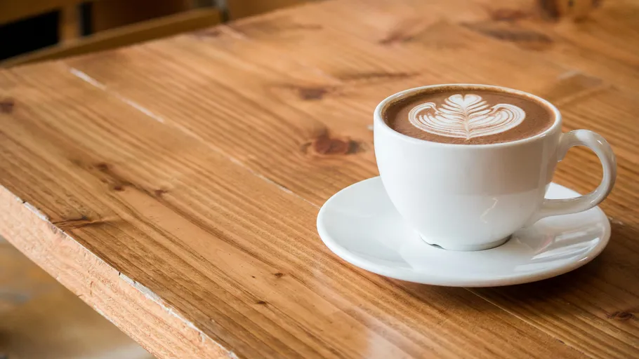 Tasse Cappuccino auf Holztisch.