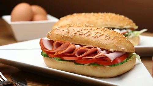 Ham sandwich with lettuce on white plate.