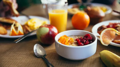 Bowl of fruit and juice on breakfast table.