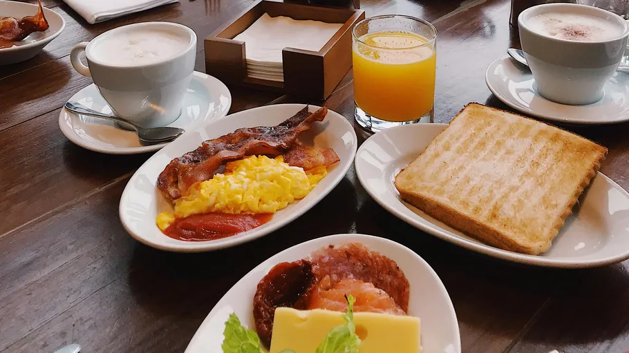 Breakfast with eggs, bacon, toast, coffee, juice.